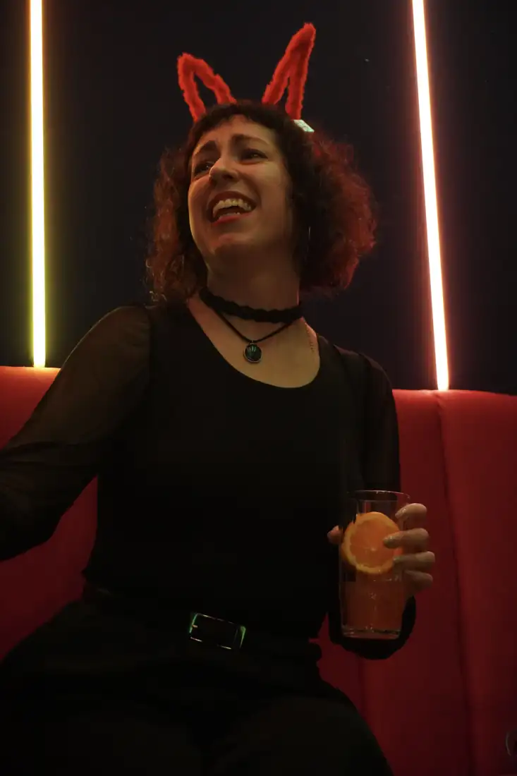 Clienta riendo con un trago en la mano en un sillón de LAF CLUB