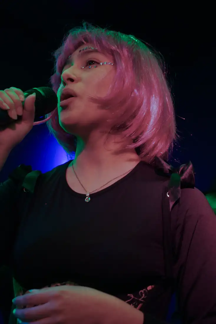 Clienta con pelo rosa cantando bajo luces de colores en LAF CLUB