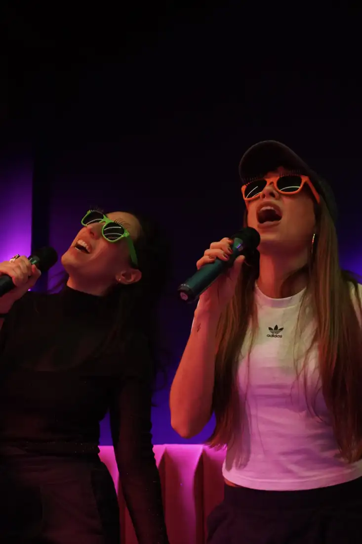 Dos clientas cantando a dúo con anteojos de fiesta en LAF CLUB